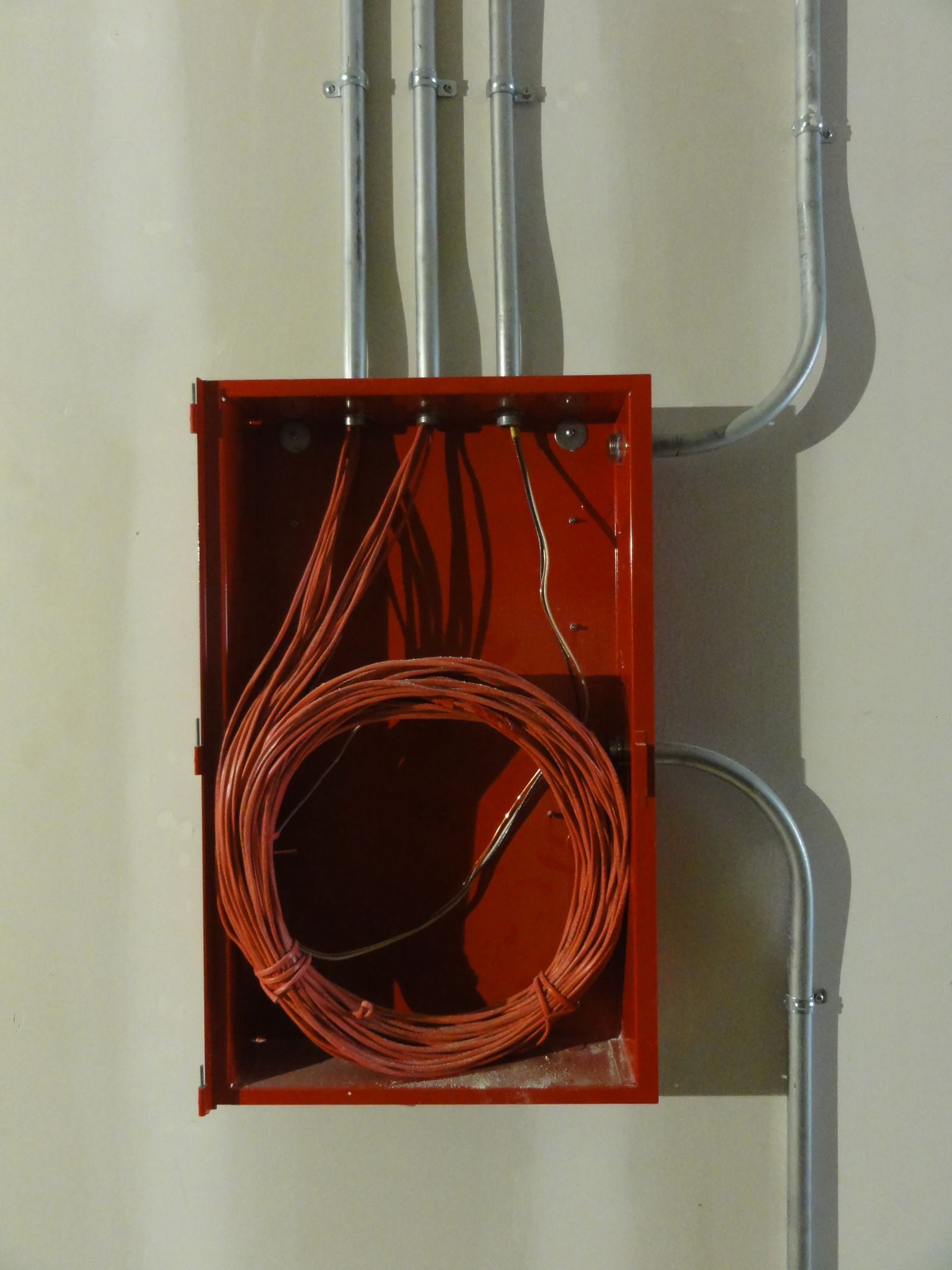 Sample image of coiled cable in a red box with metal conduit on a wall